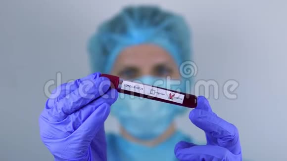 医生一个女人手里拿着一个带有冠状病毒检测阳性的试管看着它视频的预览图