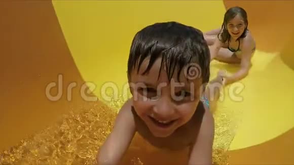 男孩和女孩正在水上公园骑着一辆橙色的滑梯视频的预览图