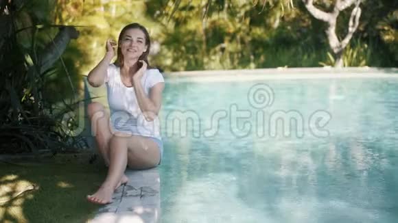 女人坐在池边用手摸着水溅起水滴视频的预览图