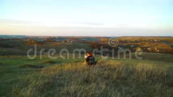 主人和宠物美国斯塔福德郡的猎犬坐在日落的青山上视频的预览图