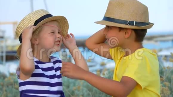 小男孩正在帮助一个可爱的女孩戴上草帽视频的预览图