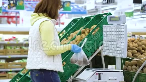 戴着面具的女人在食品店秤上称重蔬菜视频的预览图