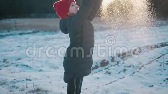 一个快乐的小女孩在一个美丽的冬天玩雪背景上的飞雪冬季概念视频的预览图