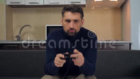 男人坐在沙发上手里拿着游戏本在游戏机上玩电子游戏并获胜视频的预览图
