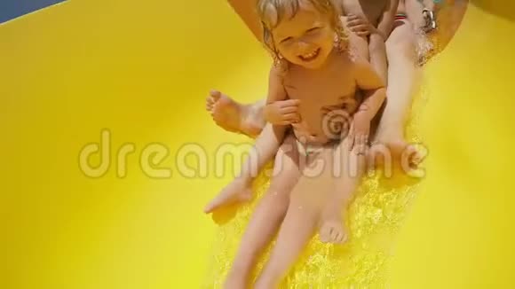 女人和快乐的孩子正在水上乐园里沿着橙色的滑梯视频的预览图
