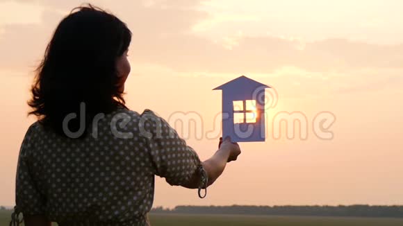 日落时剪影纸房女孩养了一个纸房子梦想着一个舒适的大房子和一个幸福的家庭视频的预览图