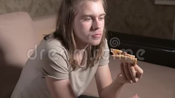 年轻人晚上坐在客厅里看电视吃披萨特写视频的预览图