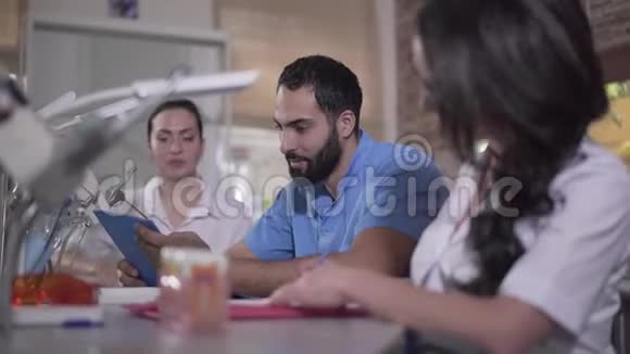 研究牙科的多民族群体成员高加索青年妇女和中东男子坐在视频的预览图