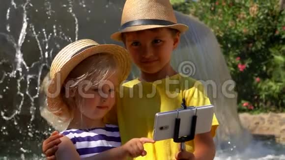 戴草帽的小男孩和小女孩在智能手机上自拍视频的预览图