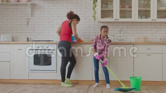 小女孩在厨房用拖把洗地板视频的预览图