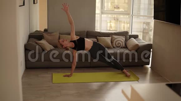 在家锻炼身体的女人练习各种瑜伽体式在客厅里做面向狗的黄色姿势视频的预览图
