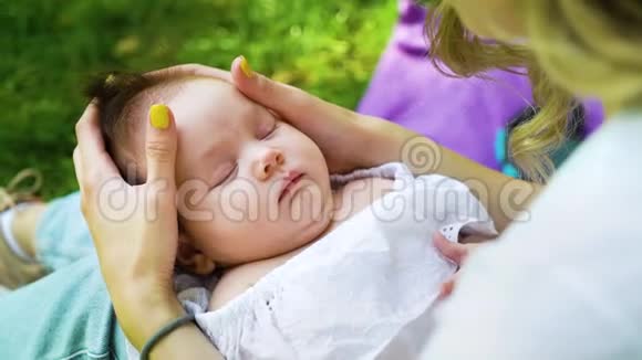 可爱的婴儿在一个婴儿睡在照顾母亲的腿外视频的预览图