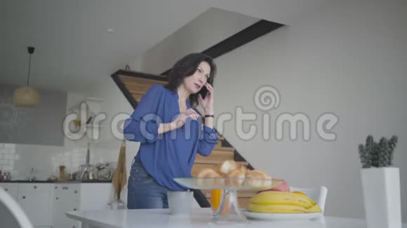 成功的白种人女商人在家里吃早餐时打电话自信的黑发肖像视频的预览图