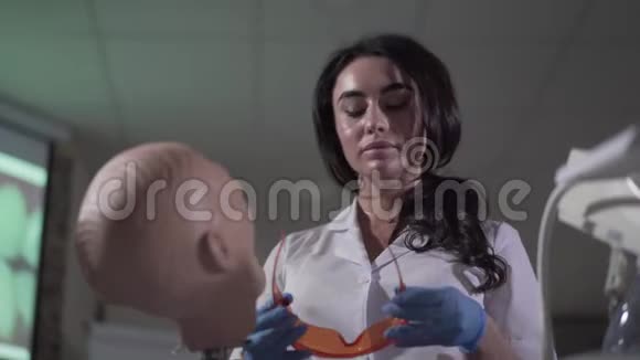 一幅严肃美丽的白人女性的肖像用牙科人体模型练习年轻的黑发助理视频的预览图