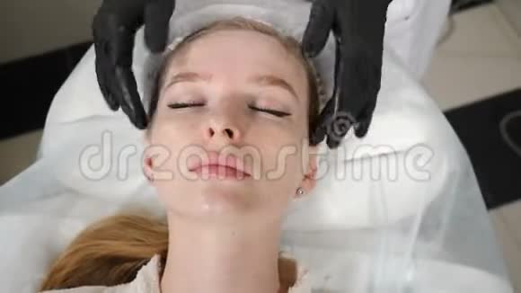 年轻女人做面部按摩放松水疗皮肤和身体护理手工雕刻面部按摩视频的预览图