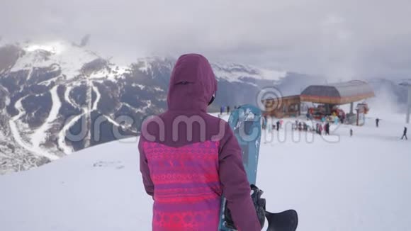 在滑雪场女孩滑雪者手里拿着滑雪板雪山上的运动女人滑雪冬季阳光明媚视频的预览图