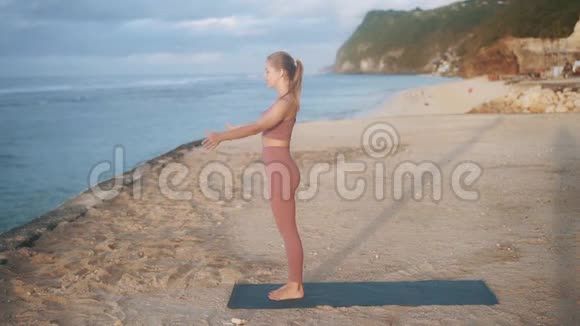 带马尾辫的苗条女孩在海滩上做山瑜伽姿势视频的预览图