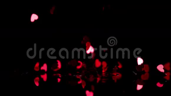 红心纸屑落在黑色背景下视频的预览图