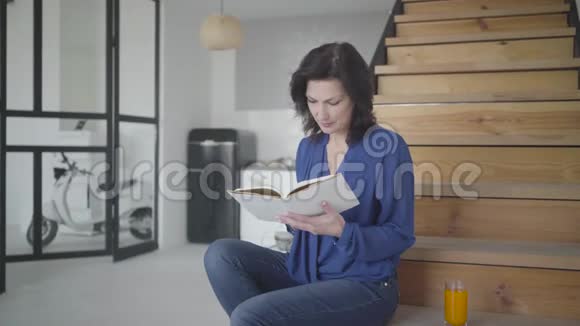 室内智能华丽女性阅读书籍的肖像布鲁内特高加索女商人在家中的楼梯上休息视频的预览图