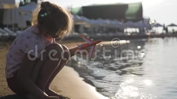 剪影女孩在日落时在热带海滩玩玩具飞机手拿小飞机特写放松时间视频的预览图