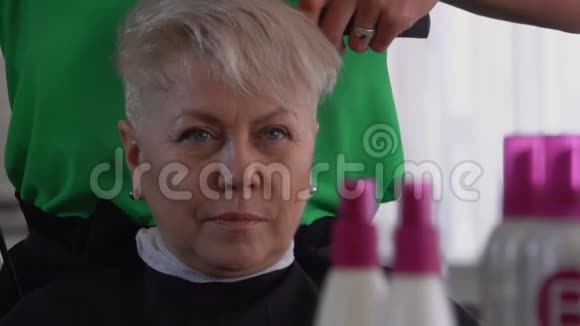 理发师正在给一位满意的女性客户剪短头发视频的预览图