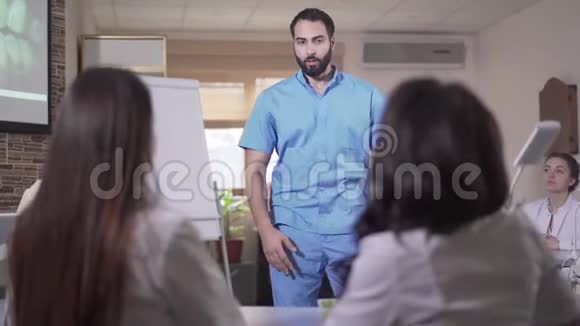 严肃英俊的中东男子穿着蓝色制服教牙科学生的肖像自信的年轻人视频的预览图