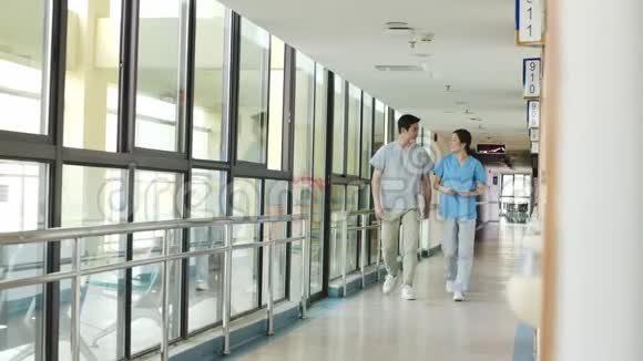 两名亚洲医疗保健专业人员在医疗设施走廊散步交谈视频的预览图