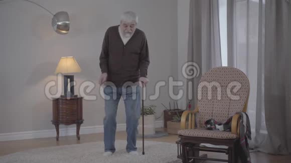 开朗成熟的白种人男人在室内用手杖跳舞领取养恤金的男性正退休人员画像视频的预览图