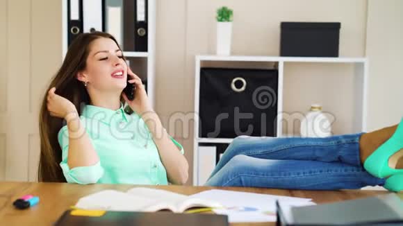 女商人在工作中放松脚在桌子上打电话视频的预览图