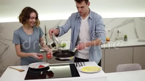 明亮的白色厨房里有一对快乐的情侣他们在平底锅上准备了煎蛋卷女朋友正在上菜还加了番茄酱视频的预览图