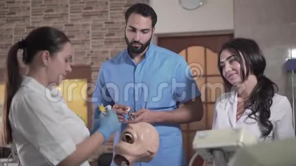 年轻的高加索妇女和中东男子使用设备操纵牙科人体模型视频的预览图