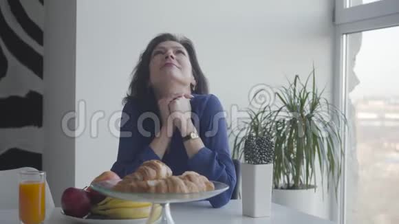 带着微笑的白种人女人在家享受早晨的肖像一位美丽的成年女士坐在桌旁视频的预览图