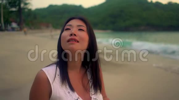 美丽快乐的亚洲女人穿着夏装享受着欢快的日落漫步在热带天堂海滩视频的预览图