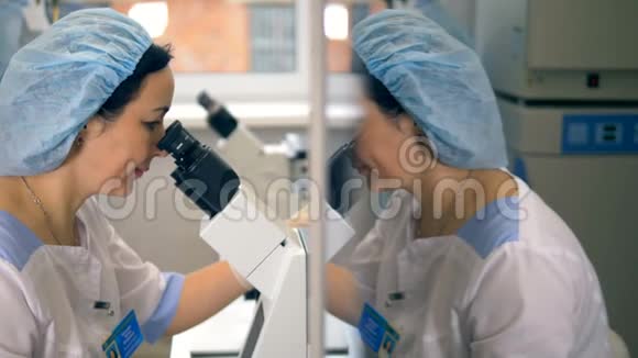 一名医疗技术人员对着显微镜照镜子的脸视频的预览图