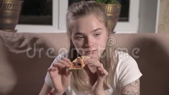 年轻可爱的女人坐在客厅沙发上看电视吃披萨特写视频的预览图