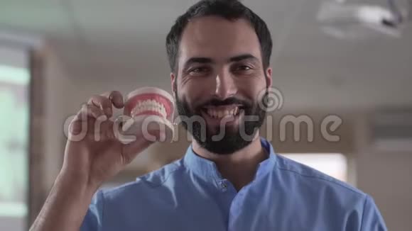 特写照片中年轻的中东男子抱着牙齿对着镜头微笑专业牙齿矫正师视频的预览图