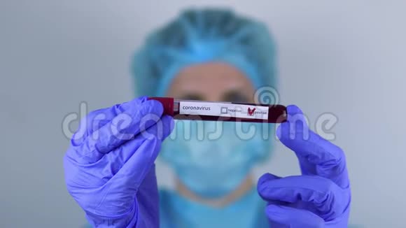 医生一个女人手里拿着一个带有冠状病毒检测阳性的试管看着它视频的预览图