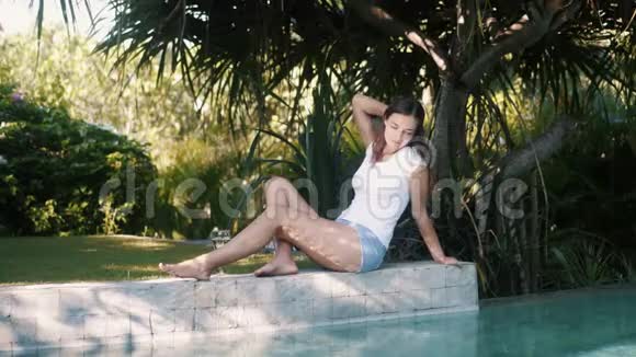 穿着休闲夏装的女人坐在泳池边休息享受假期视频的预览图