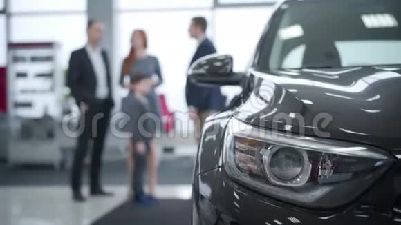 汽车前照灯的特写模糊的人在后台交谈高加索汽车经销商咨询家庭视频的预览图