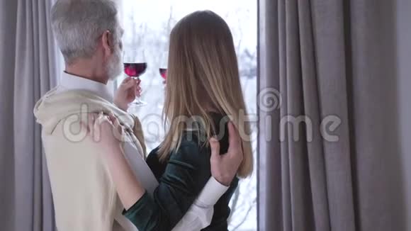 爱的高加索夫妇的背面视图年龄差异在窗前碰酒杯快乐的中年人视频的预览图