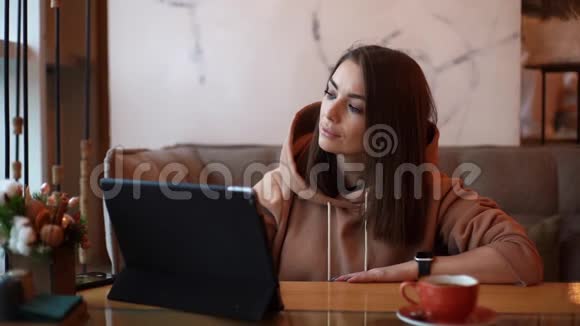 微笑美丽的白种人妇女使用数字平板电脑而坐在咖啡馆视频的预览图