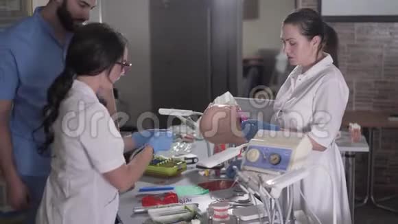 年轻的牙医助手在人体模型上安装牙齿植入物高加索女人和中东男人视频的预览图