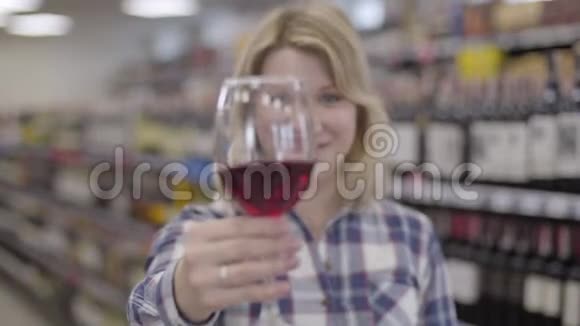 年轻的金发白种人女人把酒杯伸向镜头焦点从笑脸到酒杯再到红酒视频的预览图