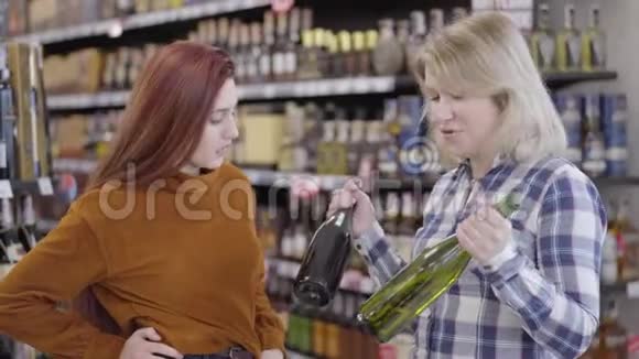 快乐的女性白种人朋友在红酒和白酒之间选择幸福的金发红发女人的画像视频的预览图