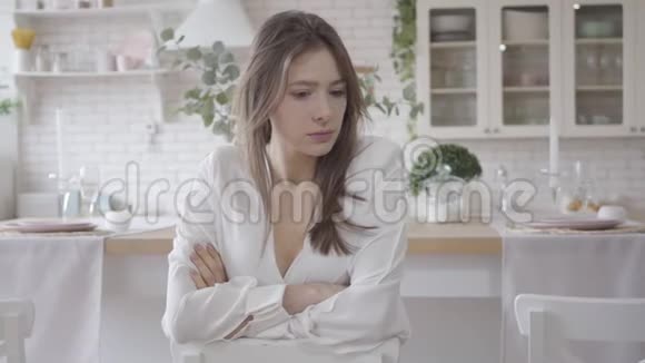 早上坐在厨房里的年轻白种人穿着紧身衣布鲁内特女孩在家思考生活方式抑郁视频的预览图
