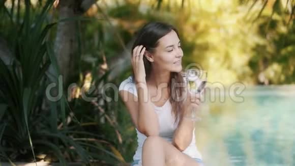 女人的画像坐在池边手里拿着一杯水微笑着视频的预览图