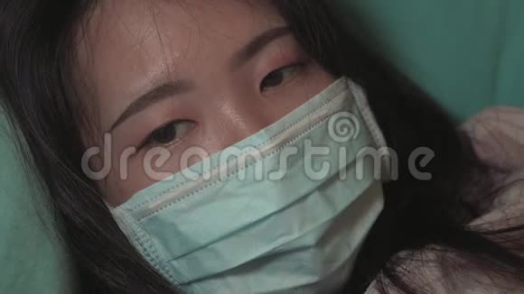 戴着医疗面具的亚洲中国妇女在19号封锁检疫期间在家中的沙发上焦虑和恐惧视频的预览图