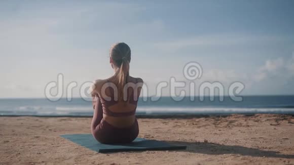 女孩用瑜伽姿势提腿伸展身体沙滩视频的预览图