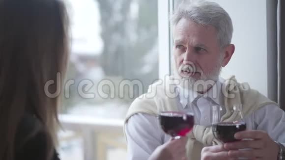 高加索族男子的特写镜头与面目全非的年轻女子碰杯喝红酒快乐的白发视频的预览图