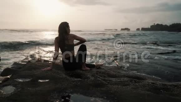 女人在海滩上做伸展运动在背景上做海洋慢动作视频的预览图
